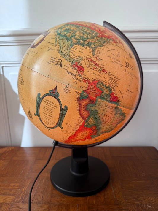 Globe lumineux Razzia, design vintage danois, avec cartographie ancienne, éclairage doux, sur une surface en bois.