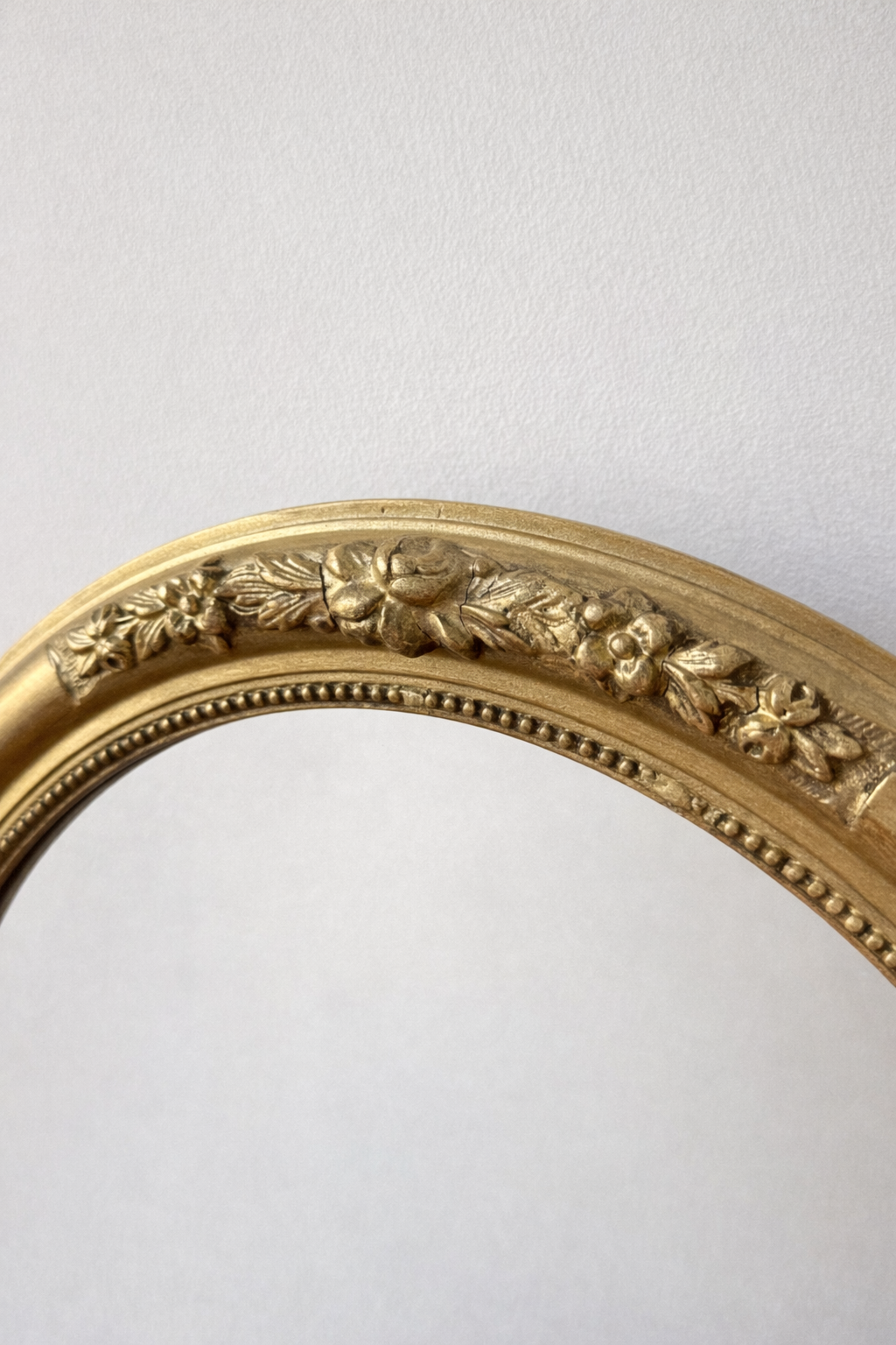 Miroir doré ovale style victorien avec cadre floral, décoration élégante pour salon ou chambre.