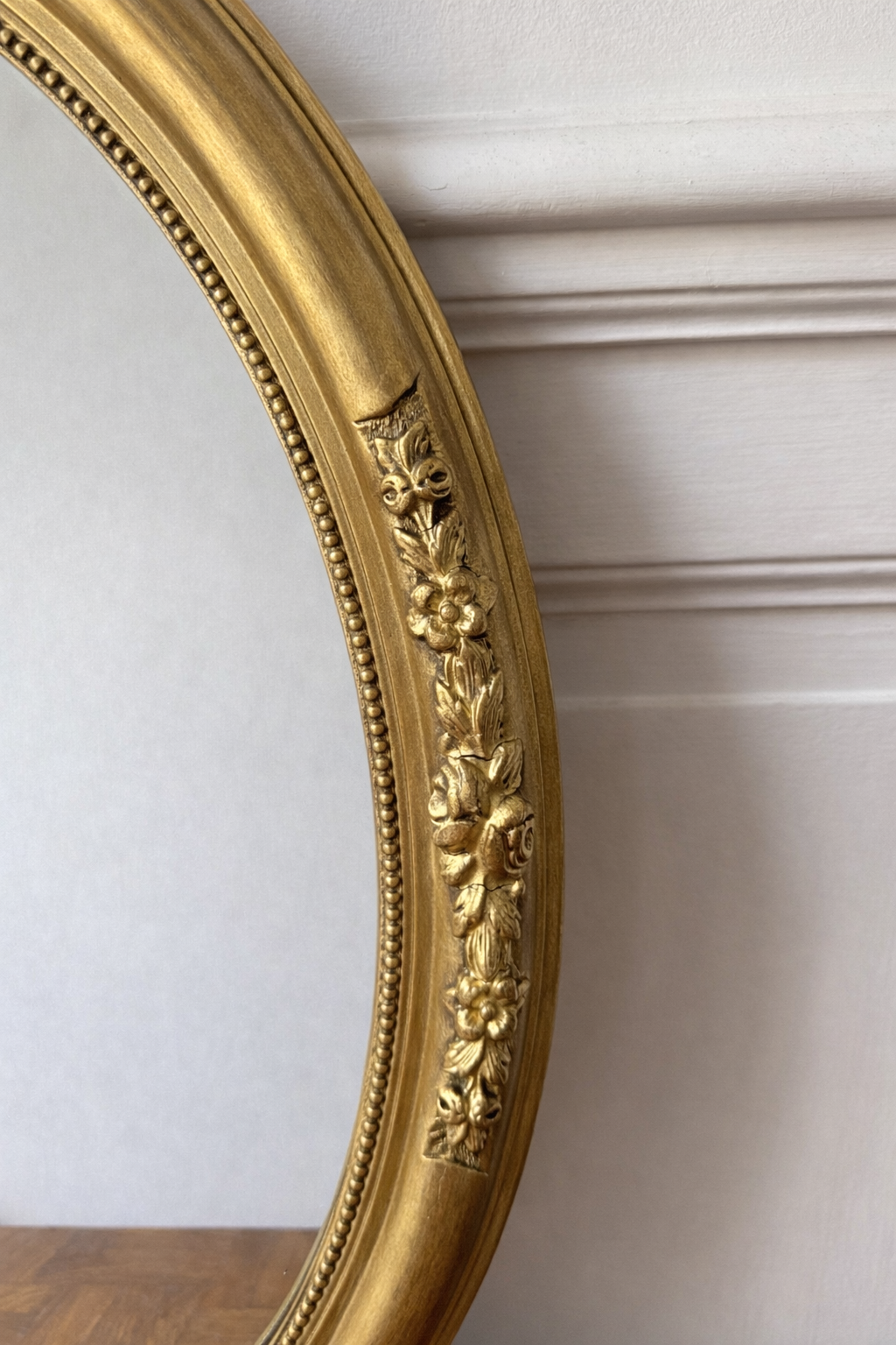Miroir ovale doré style victorien avec cadre orné de fleurs, décoration élégante pour salon ou chambre.