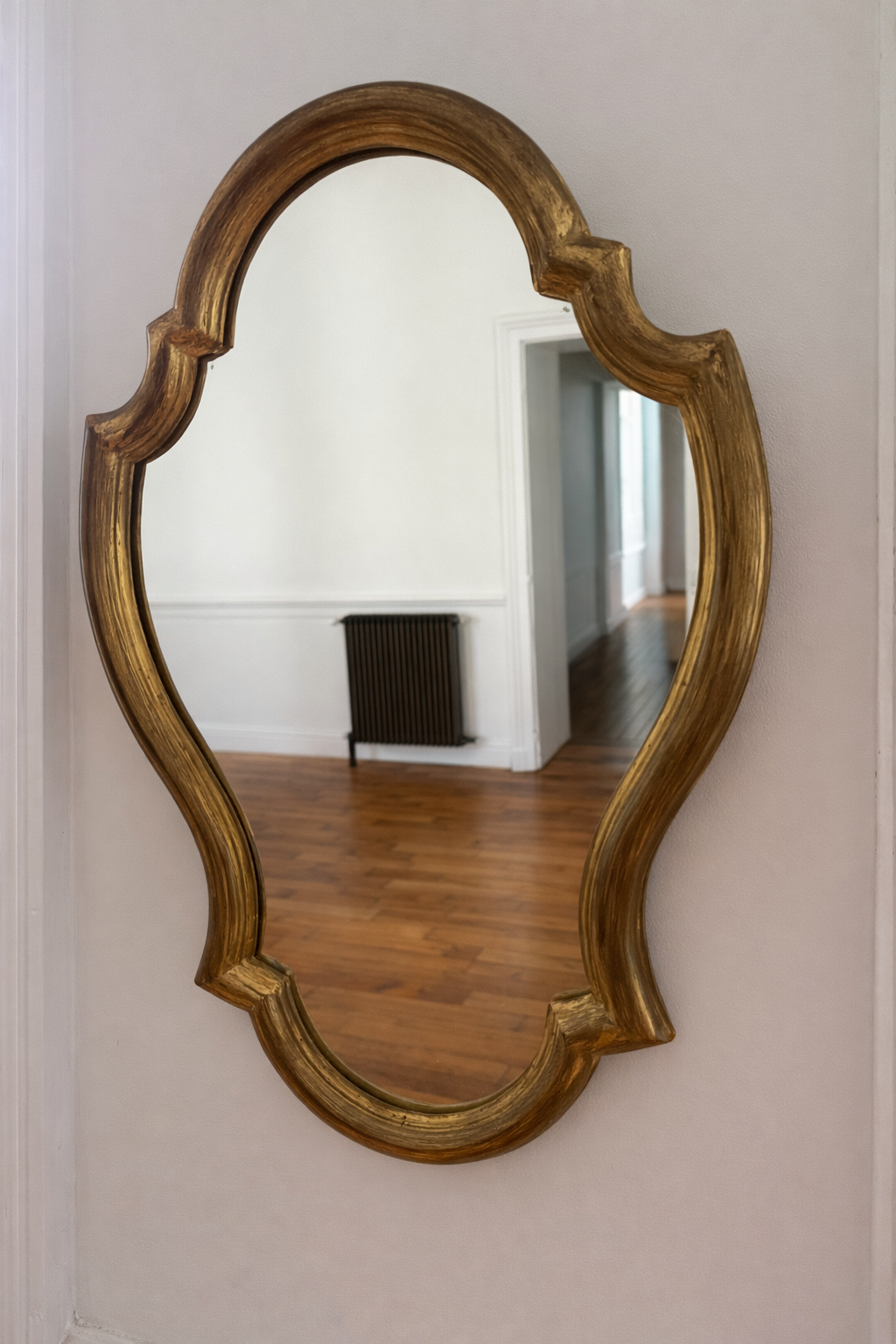 Miroir baroque en bois doré de style antique, avec cadre orné et détails sculptés, refletant un design élégant et sophistiqué.