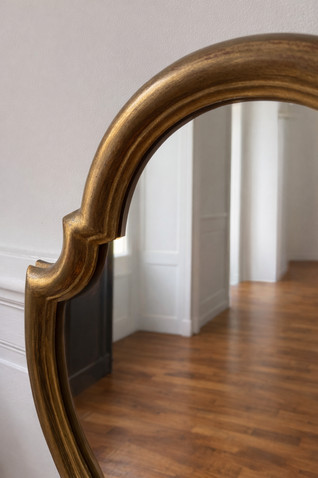 Miroir baroque en bois doré de style classique, avec cadre orné et détails sculptés, reflétant une élégance sophistiquée.