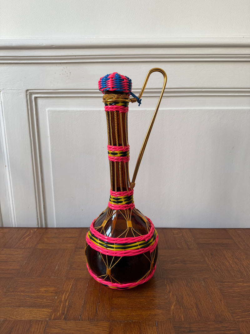 Colorful Razzia Days Bouteille scoubidou with woven plastic strands, showcasing vibrant, twisted design on a plain background.