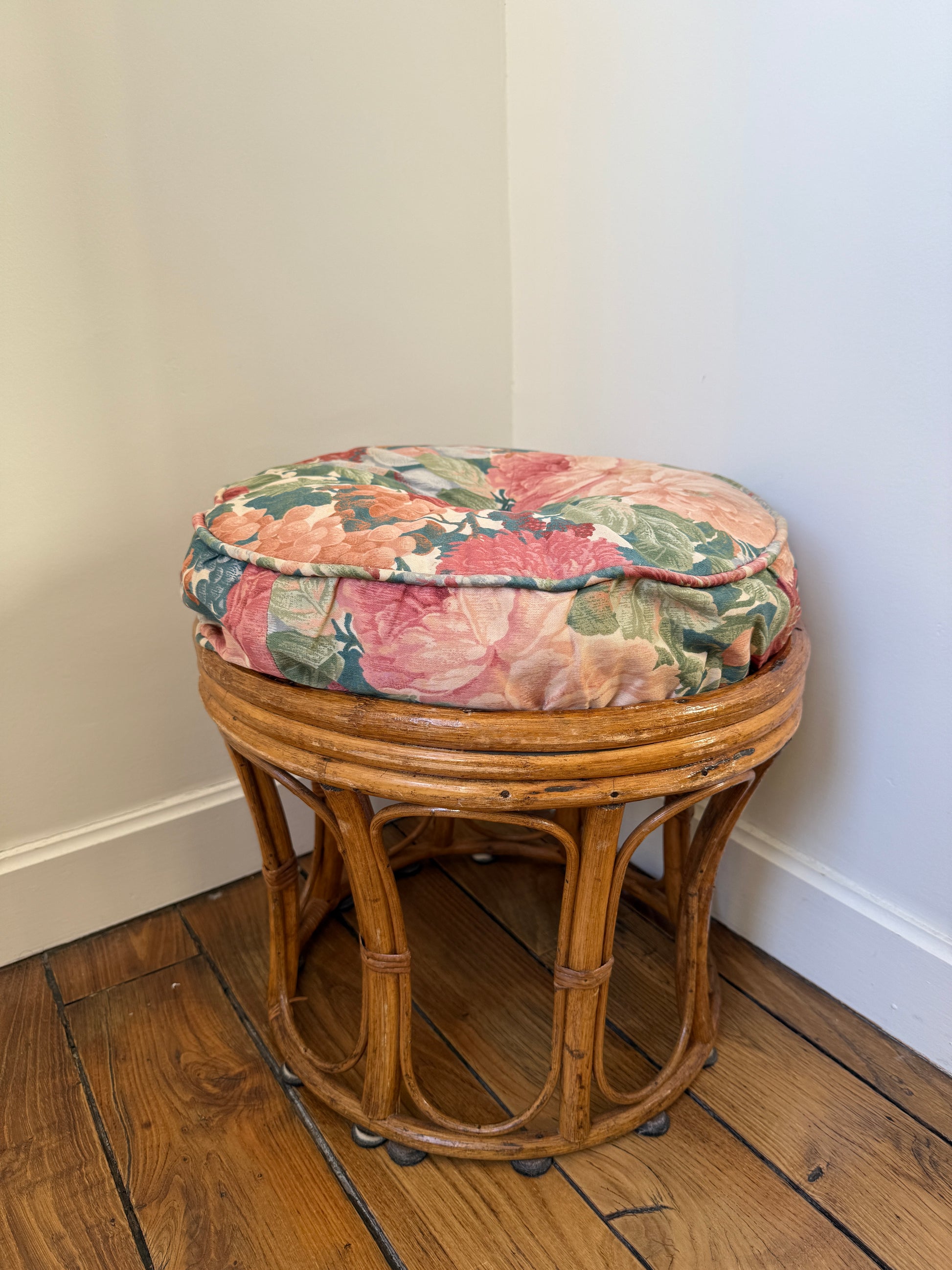 Vintage Razzia rattan stool with cushioned fabric seat, showcasing intricate woven design and plush padding for comfortable seating.