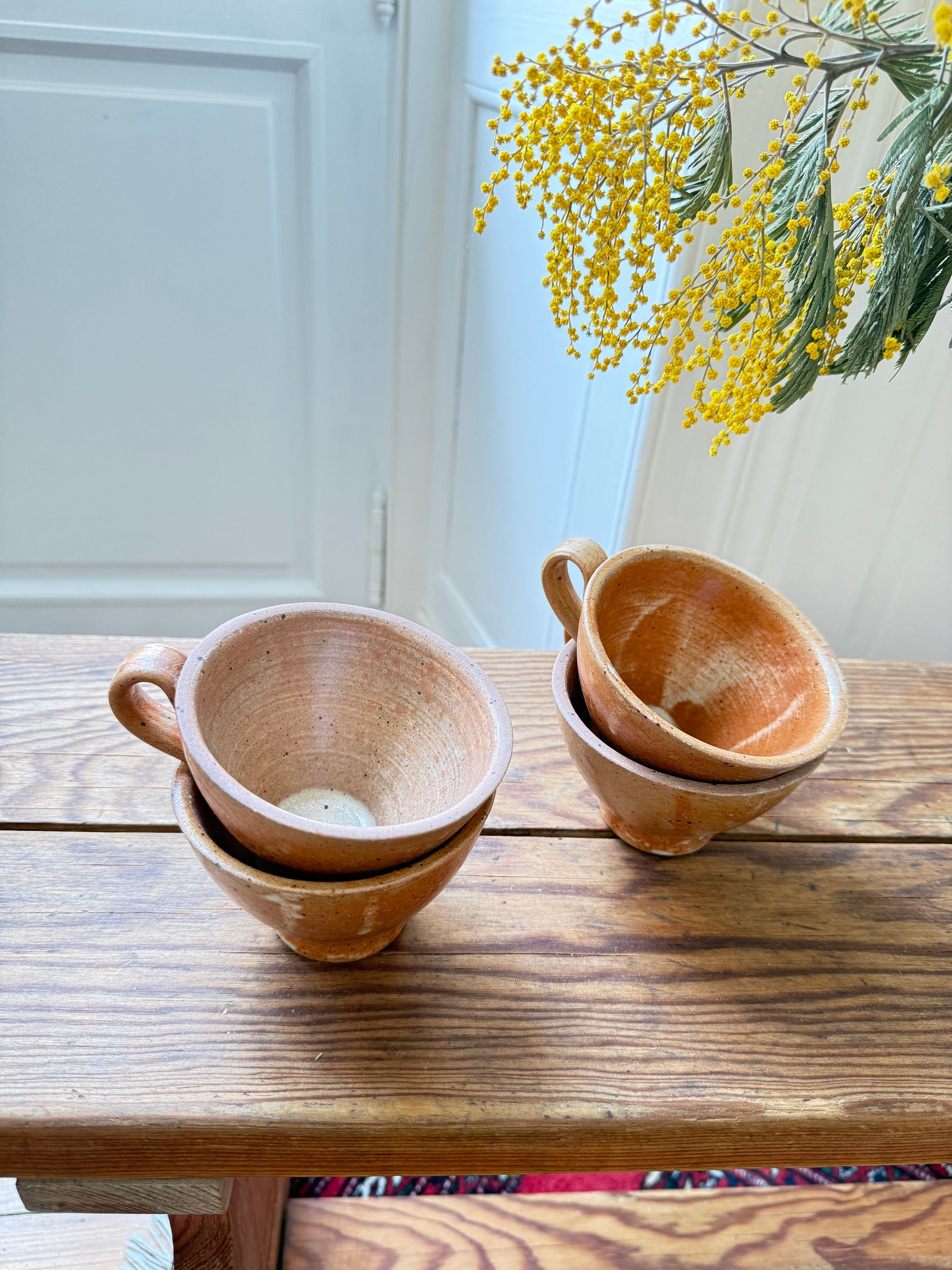 Set of four artisanal Razzia stoneware mugs with rustic, handcrafted design and textured finish on a neutral background.