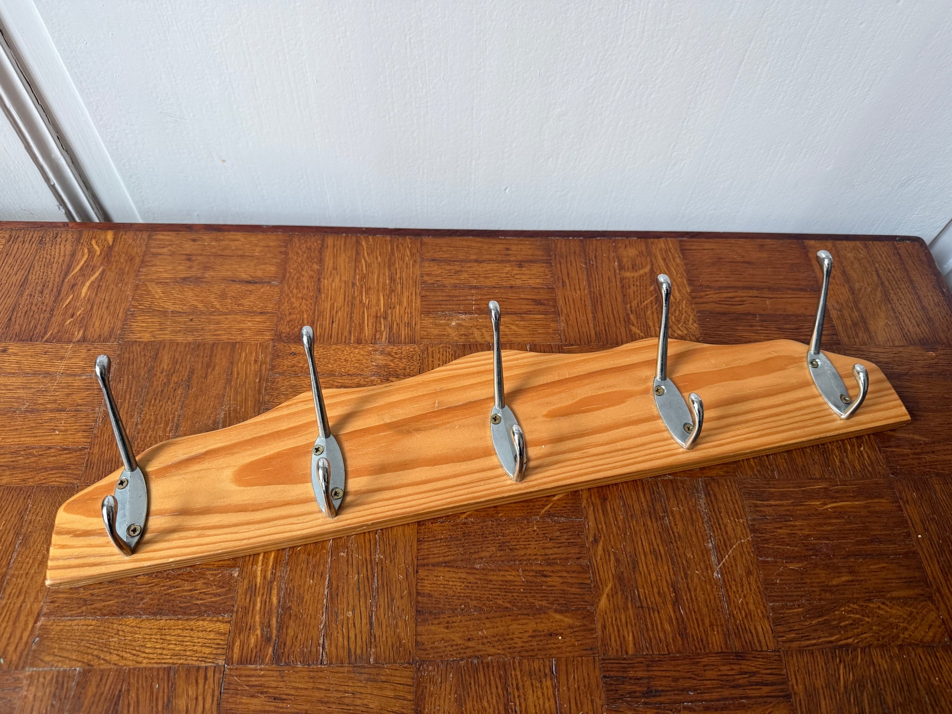 Wood and metal wall coat rack by Razzia with hooks and shelves for organizing entryways or living spaces.