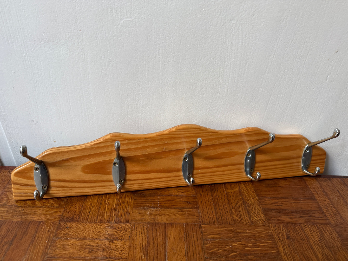 Wood and metal wall coat rack by Razzia with hooks and shelves, mounted on a modern wooden and metal wall.