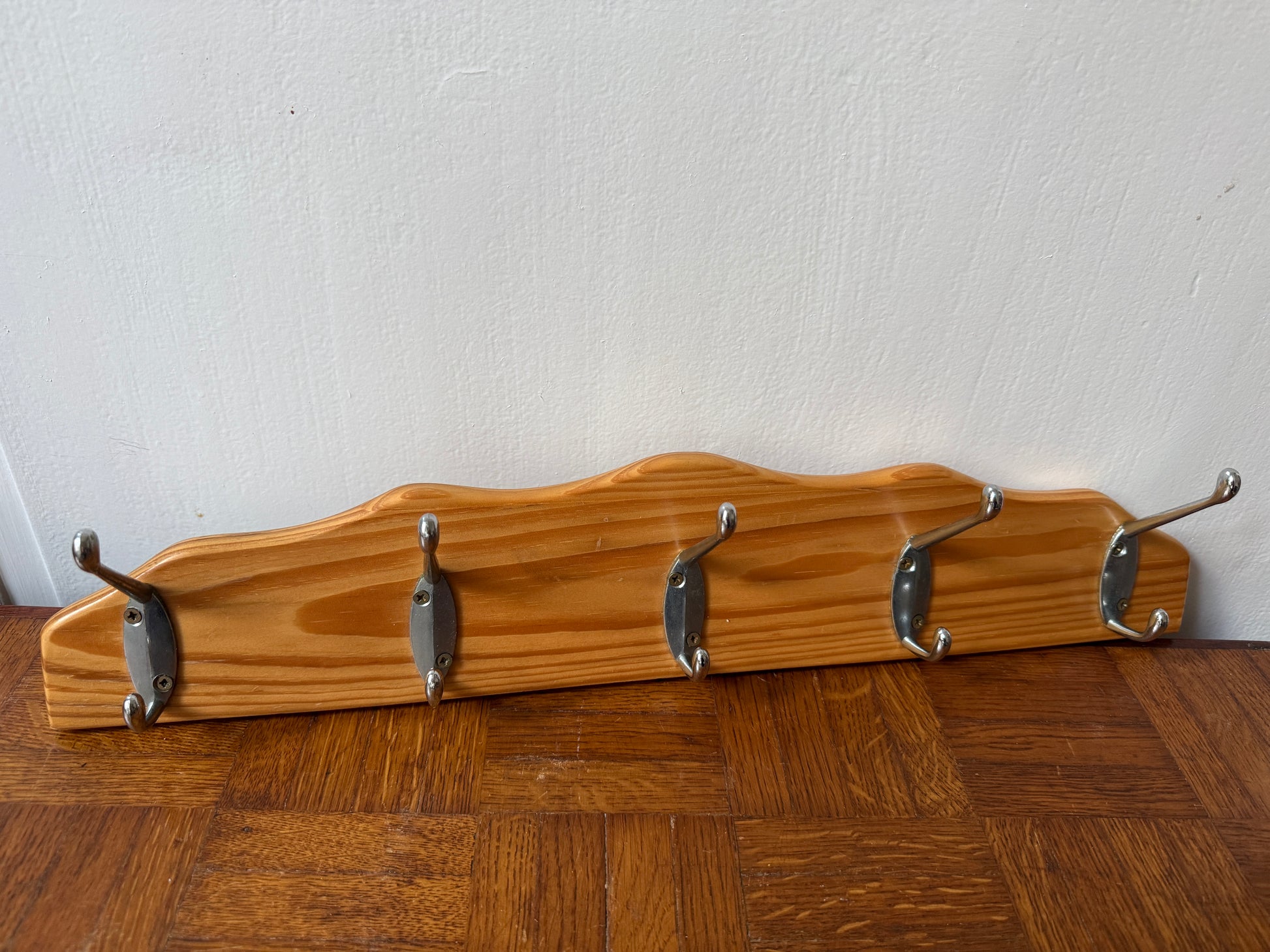 Wood and metal wall coat rack by Razzia with hooks and shelves, mounted on a modern wooden and metal wall.