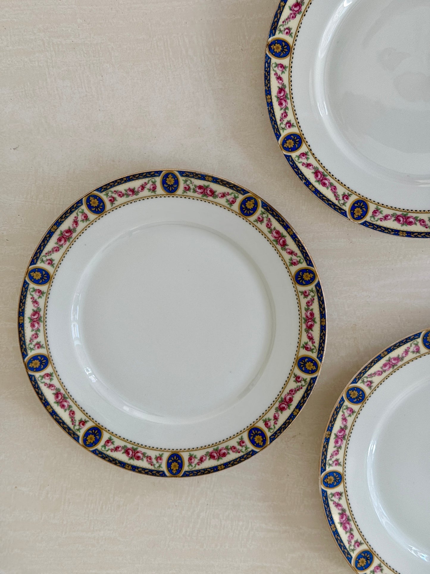 Set of 7 Razzia Limoges porcelain dinner plates with elegant white design, stacked neatly on a wooden surface.
