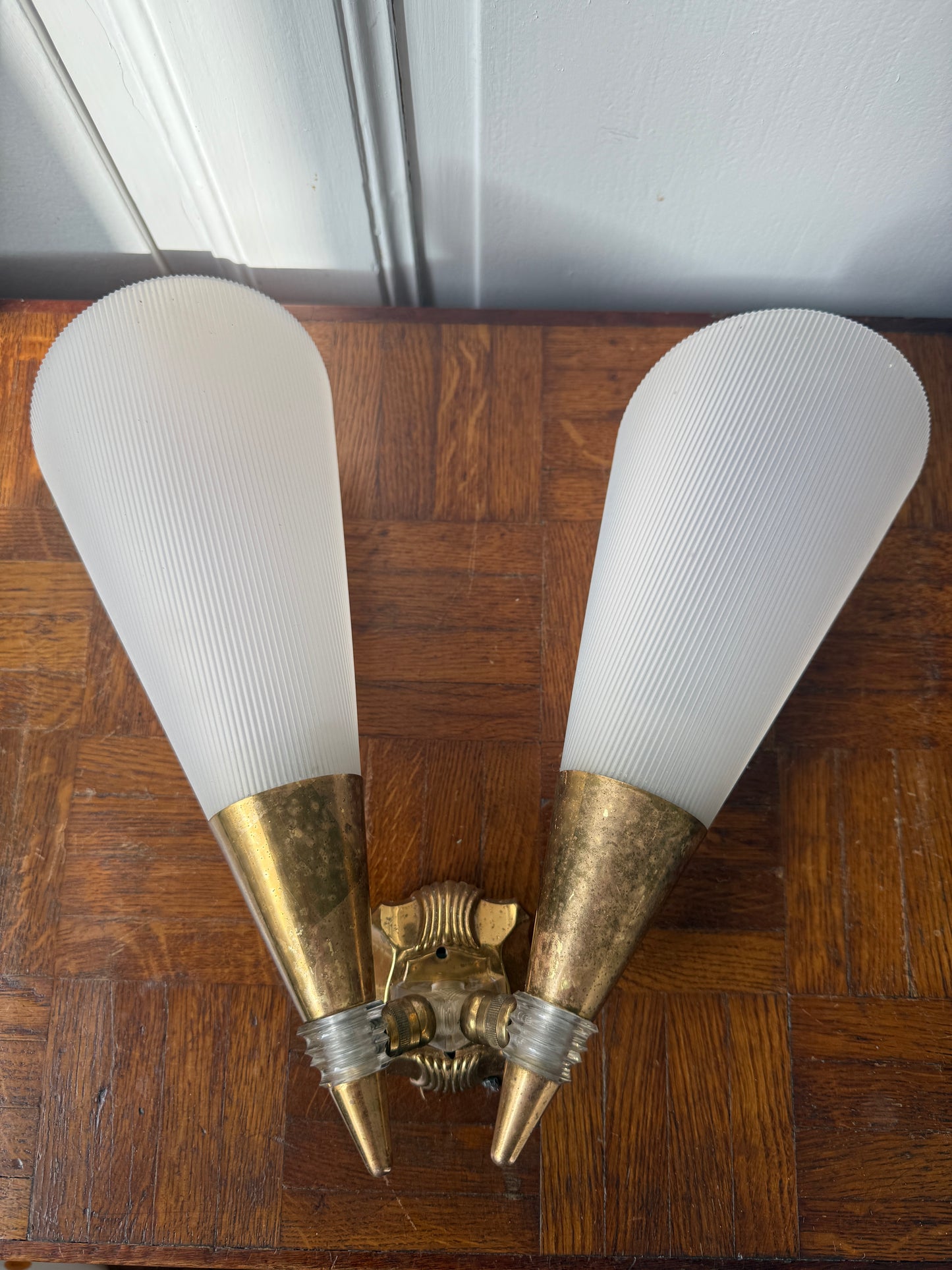 Modern brass and plastic wall applique light fixture with sleek design, featuring a brass arm and plastic shade.