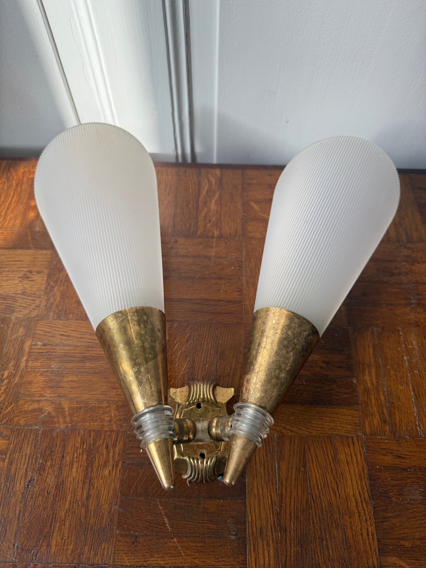Razzia wall sconce with brass and plastic components, featuring a modern design and visible mounting details.
