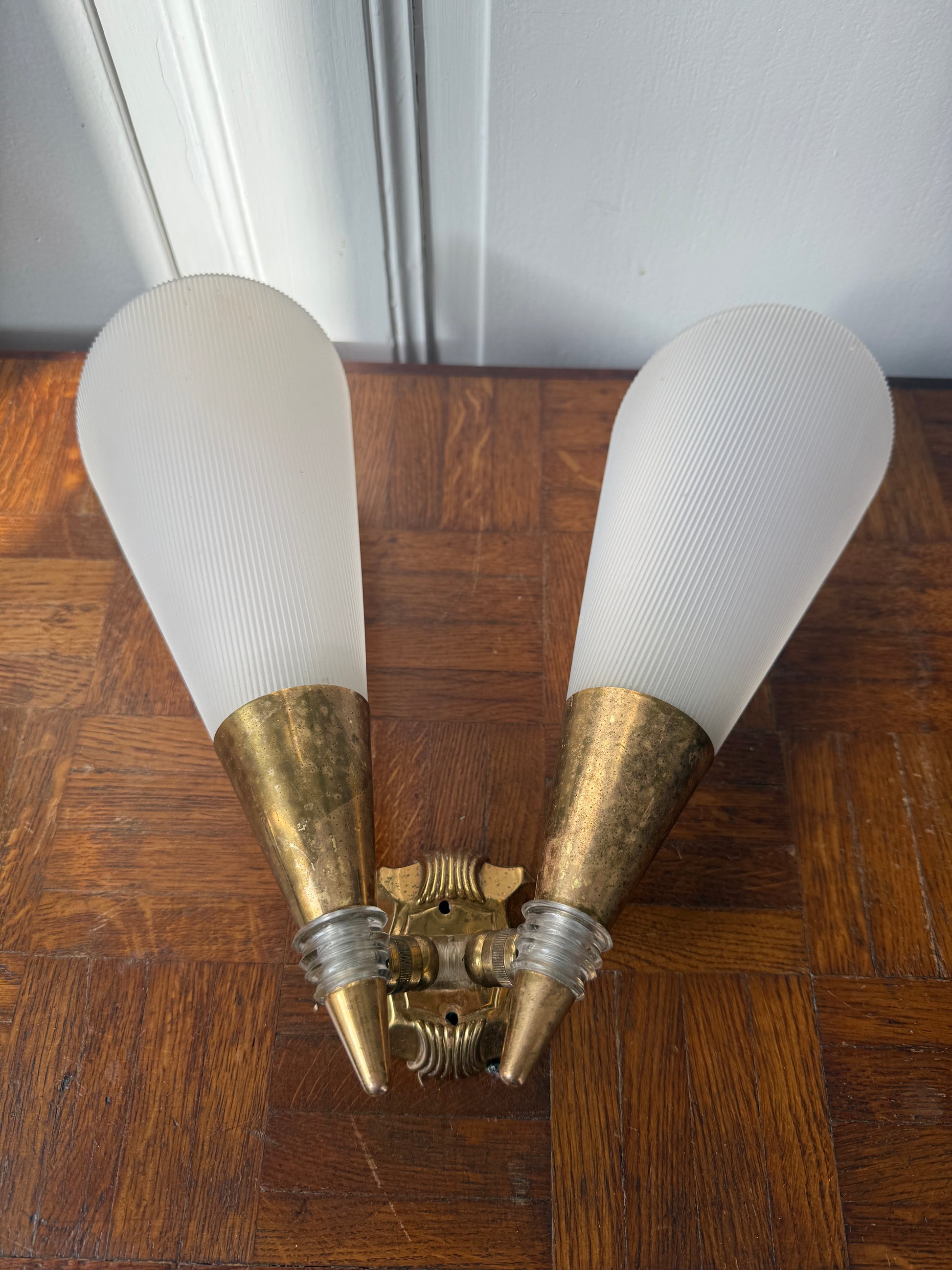 Razzia wall sconce with brass and plastic components, featuring a modern design and visible mounting details.