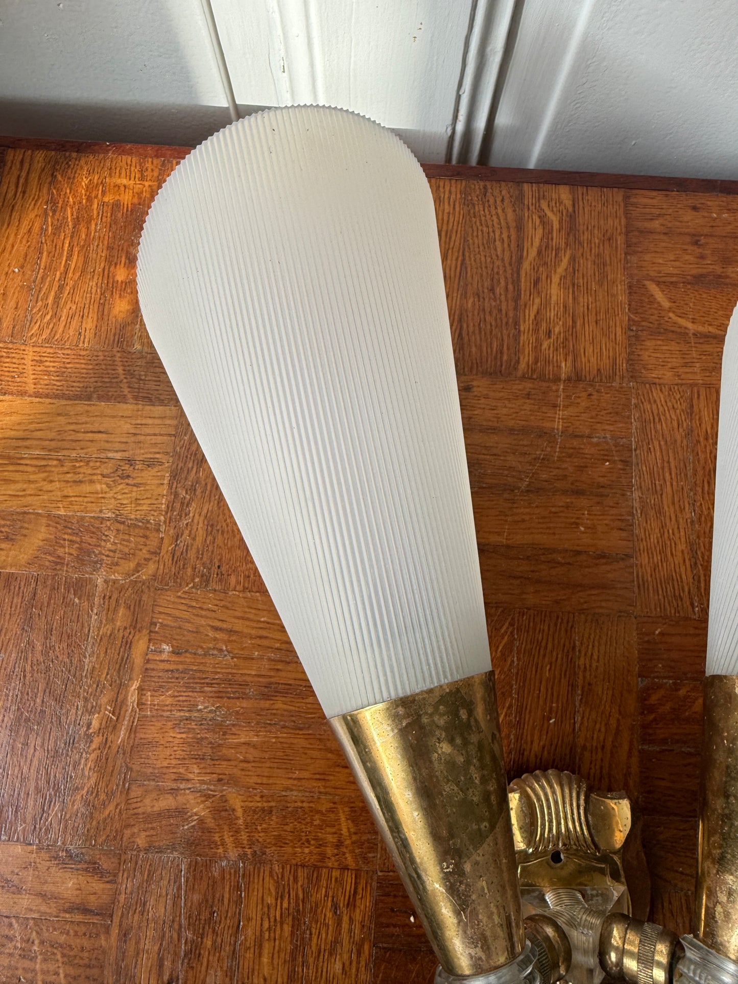 Razzia brass and plastic wall applique with modern design, featuring a sleek brass arm and white plastic shade.