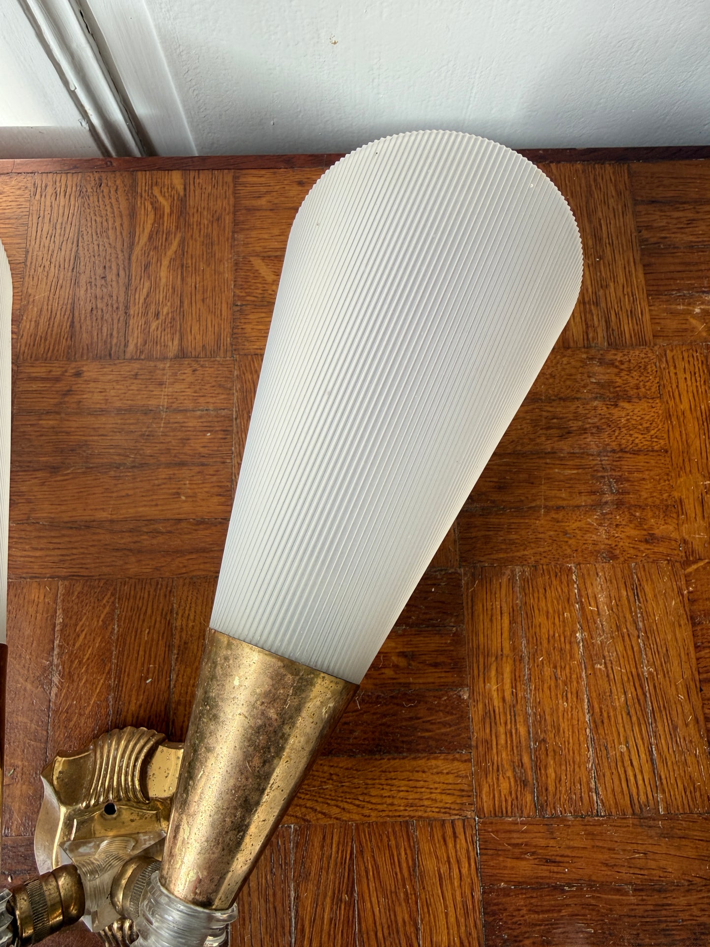 Razzia wall lamp with brass and plastic applique, featuring a modern design and sleek finish, mounted on a wall.