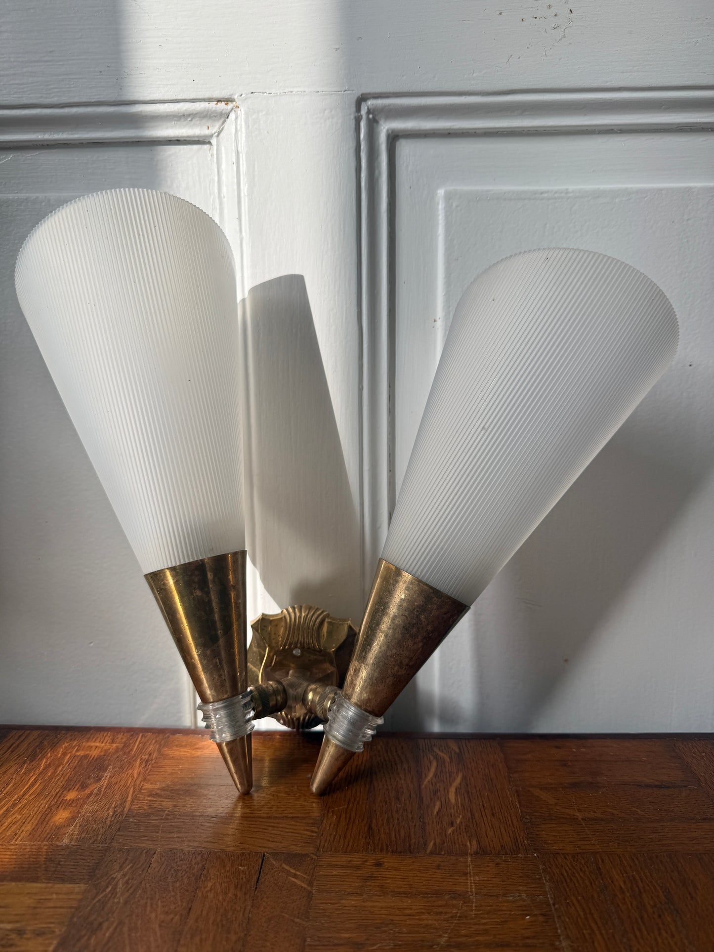 Razzia wall sconce with brass and plastic design, featuring a modern, minimalist style against a neutral background.