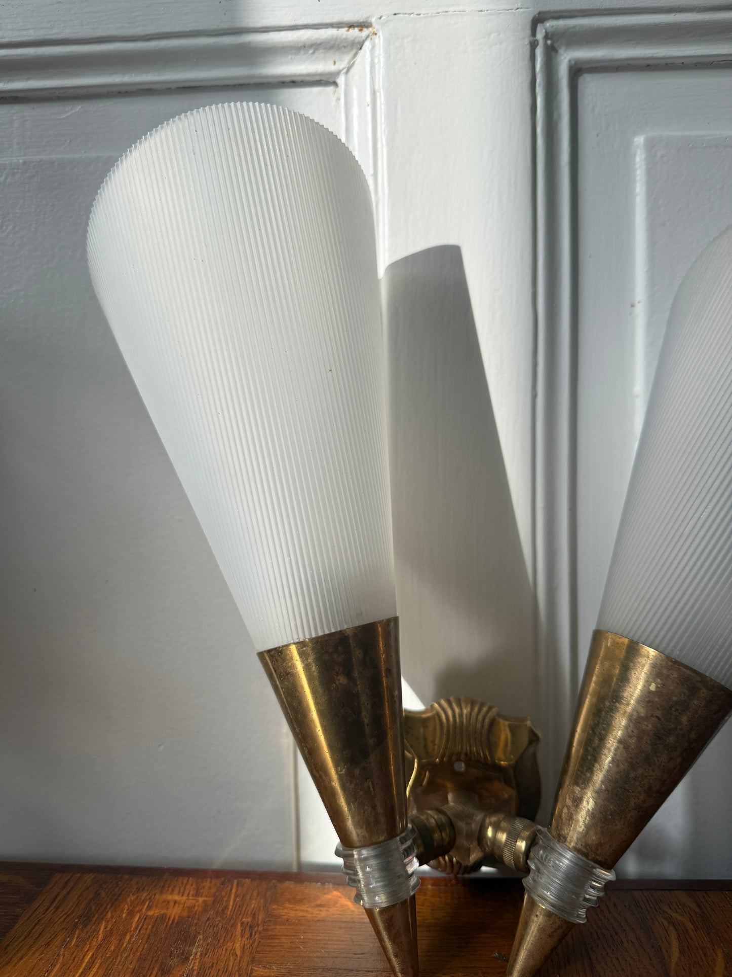 Razzia wall sconce with brass and plastic design, featuring a sleek, modern look and a cylindrical shade mounted on a wall.