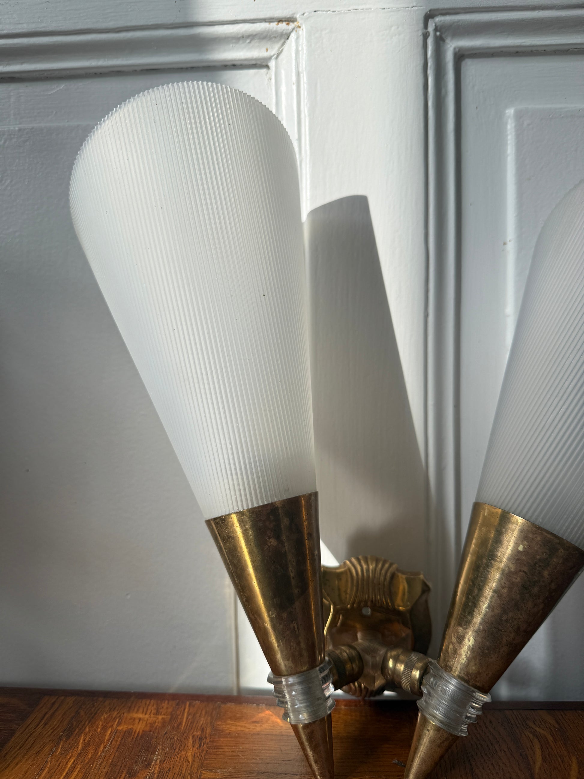 Razzia wall sconce with brass and plastic design, featuring a sleek, modern look and a cylindrical shade mounted on a wall.