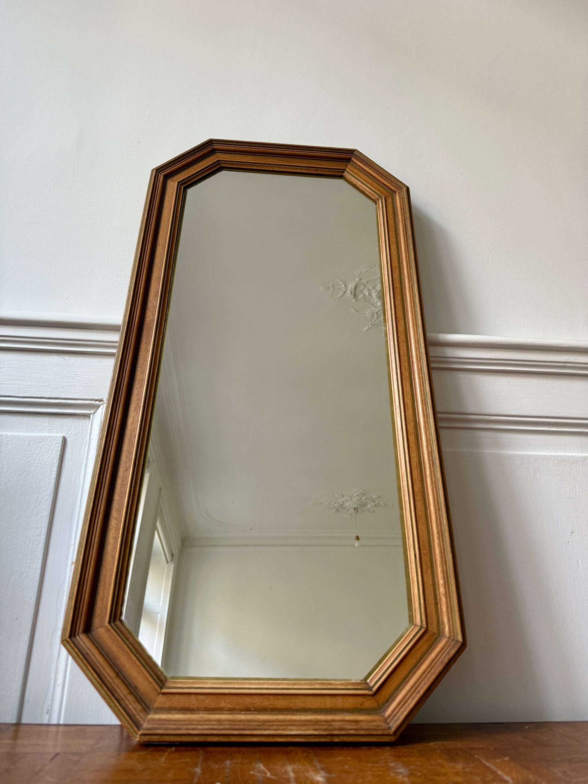 Miroir octogonal nervuré en bois doré Razzia, avec cadre élégant en bois sculpté, reflet dans un intérieur moderne.