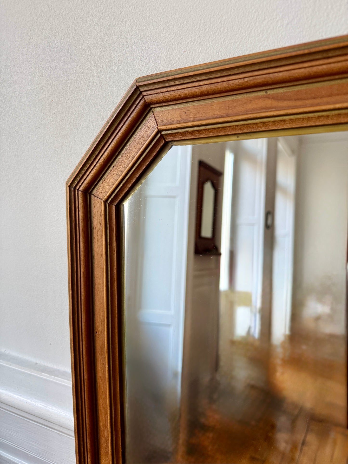 Miroir octogonal nervuré en bois doré Razzia, avec cadre orné de détails élégants, reflet dans une pièce lumineuse.