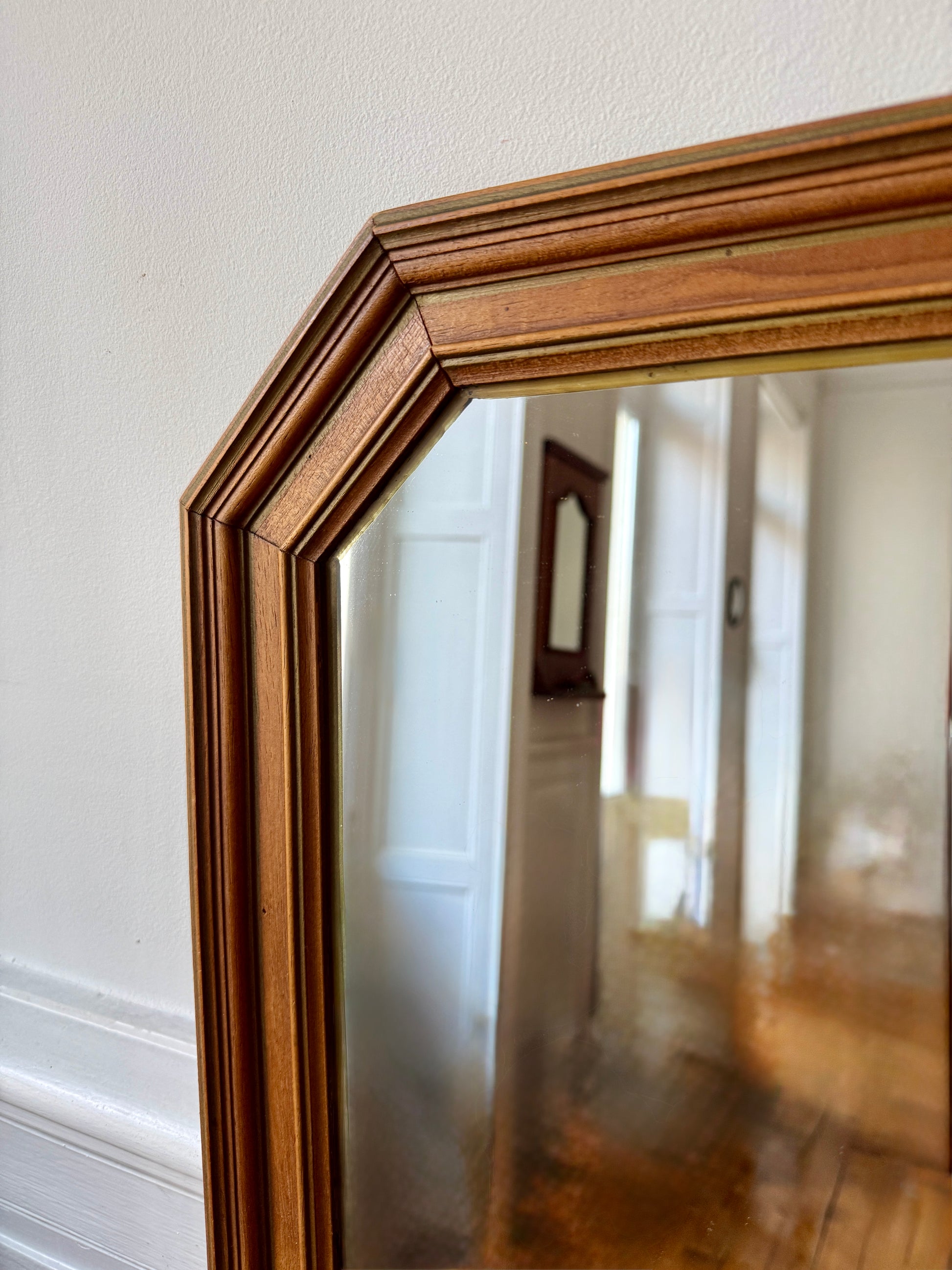 Miroir octogonal nervuré en bois doré Razzia, avec cadre orné de détails élégants, reflet dans une pièce lumineuse.