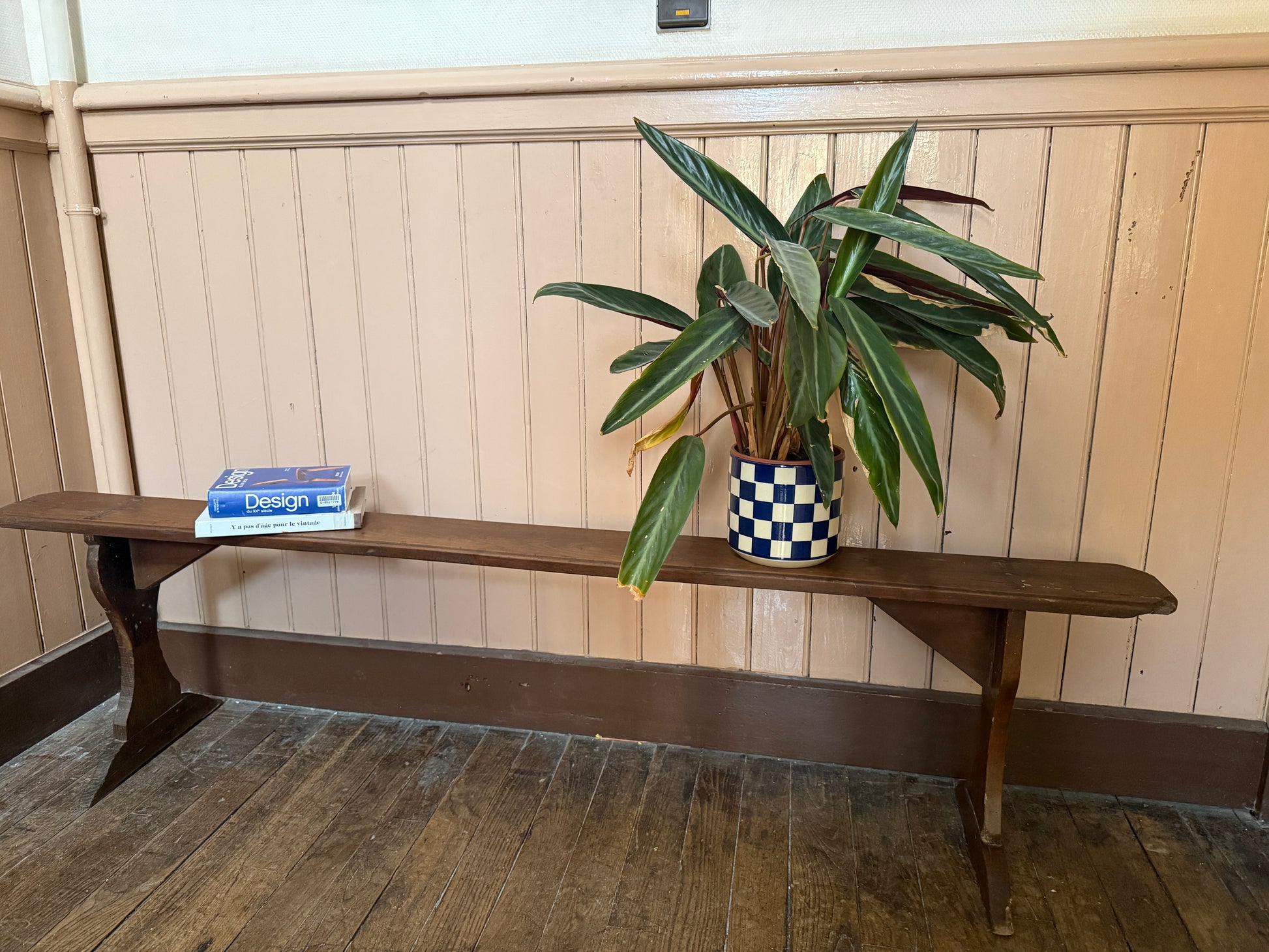 Ancien banc en bois robuste de la marque Razzia, avec une finition patinée et un design vintage, posé sur un sol en pierre.