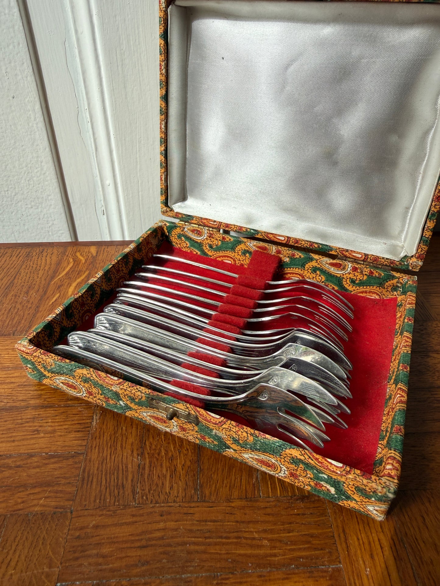 Set de 12 fourchettes à dessert en argent Razzia, élégantes et brillantes, disposées sur une surface blanche.