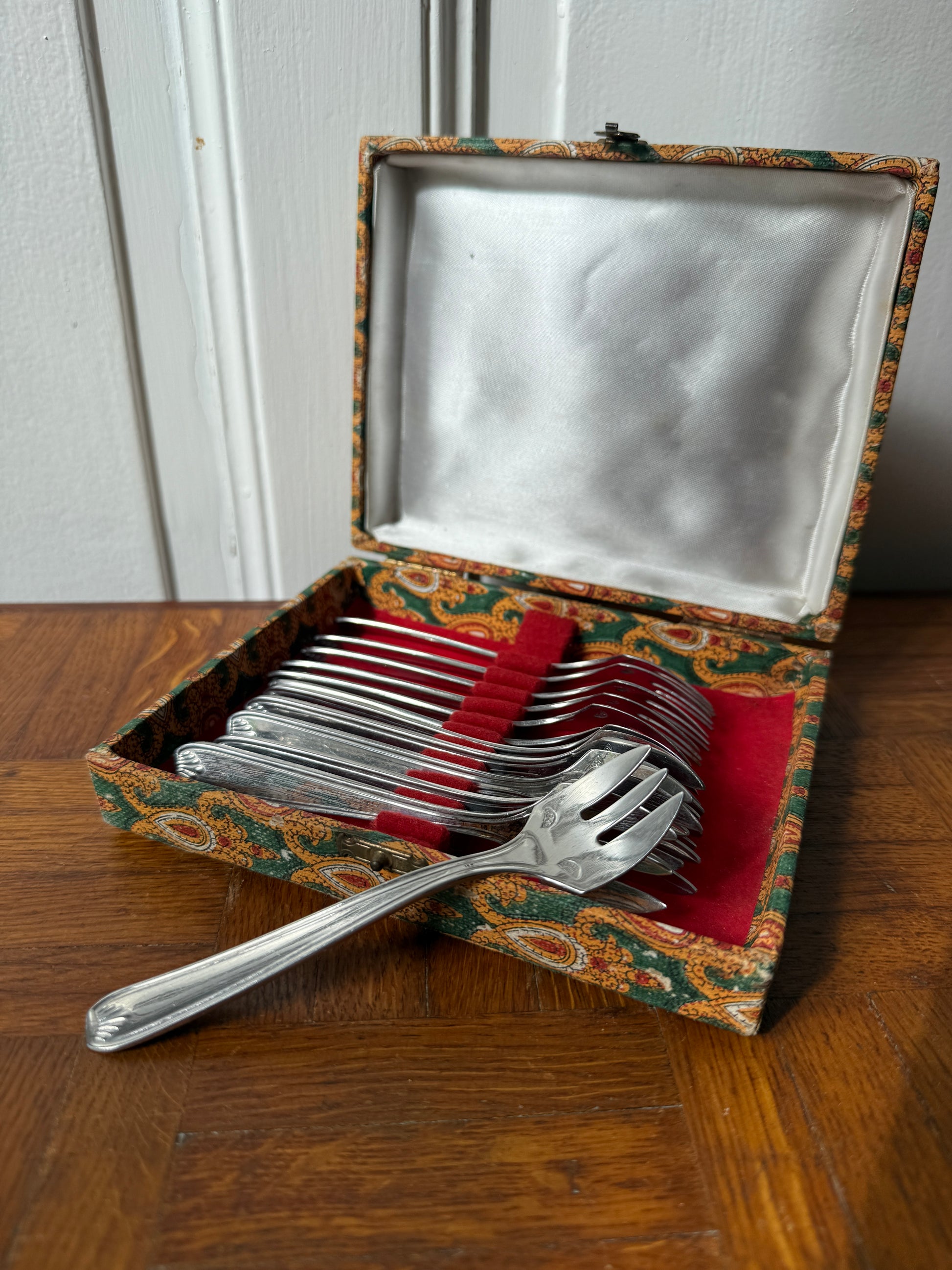 12 fourchettes à dessert en argent Razzia, élégantes et finement conçues, disposées sur une surface blanche.