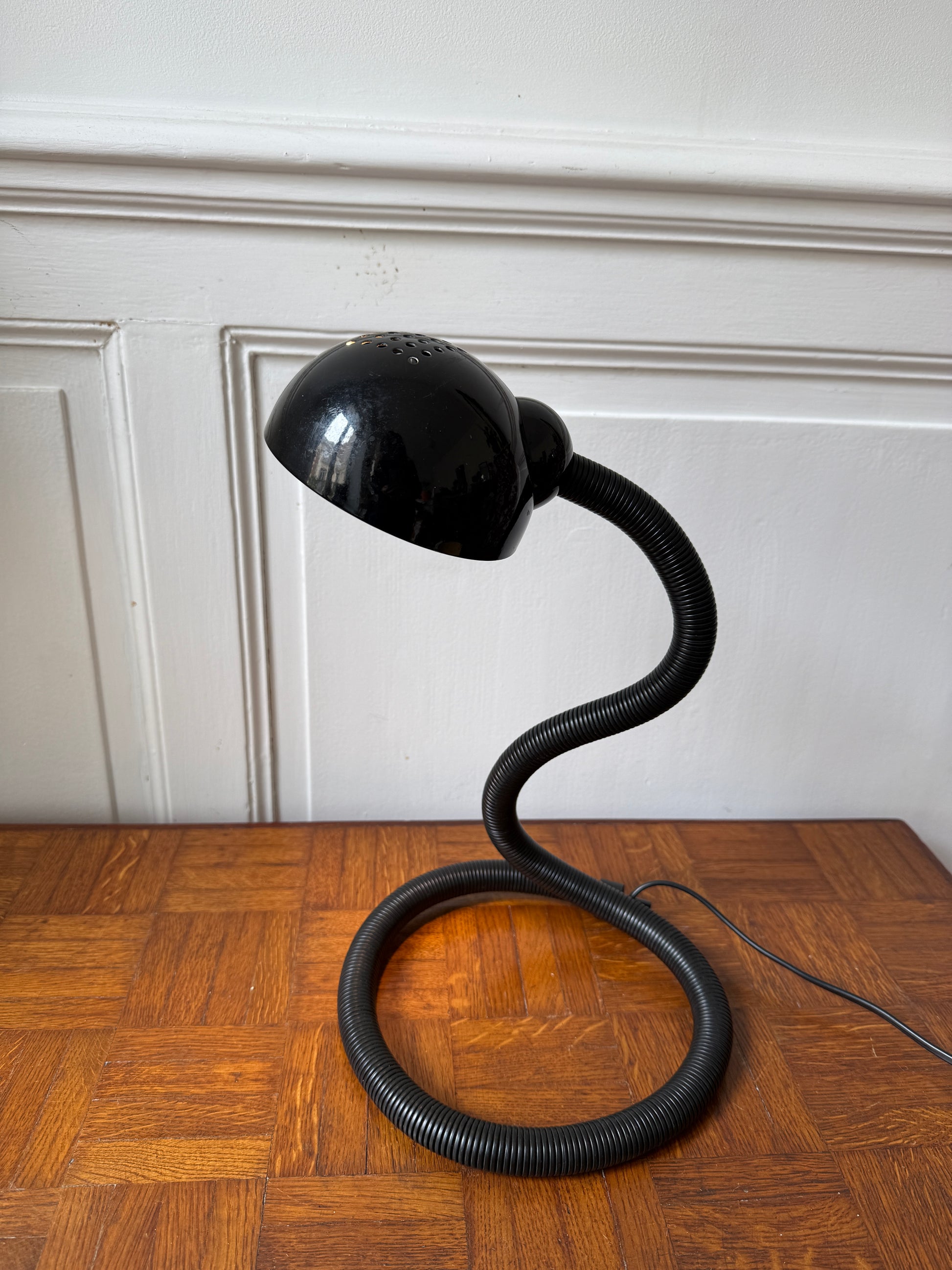 Lampe flexible “Hebi” de Razzia conçue par Isao Hosoe, avec un bras articulé en métal noir et une tête de lampe ronde.