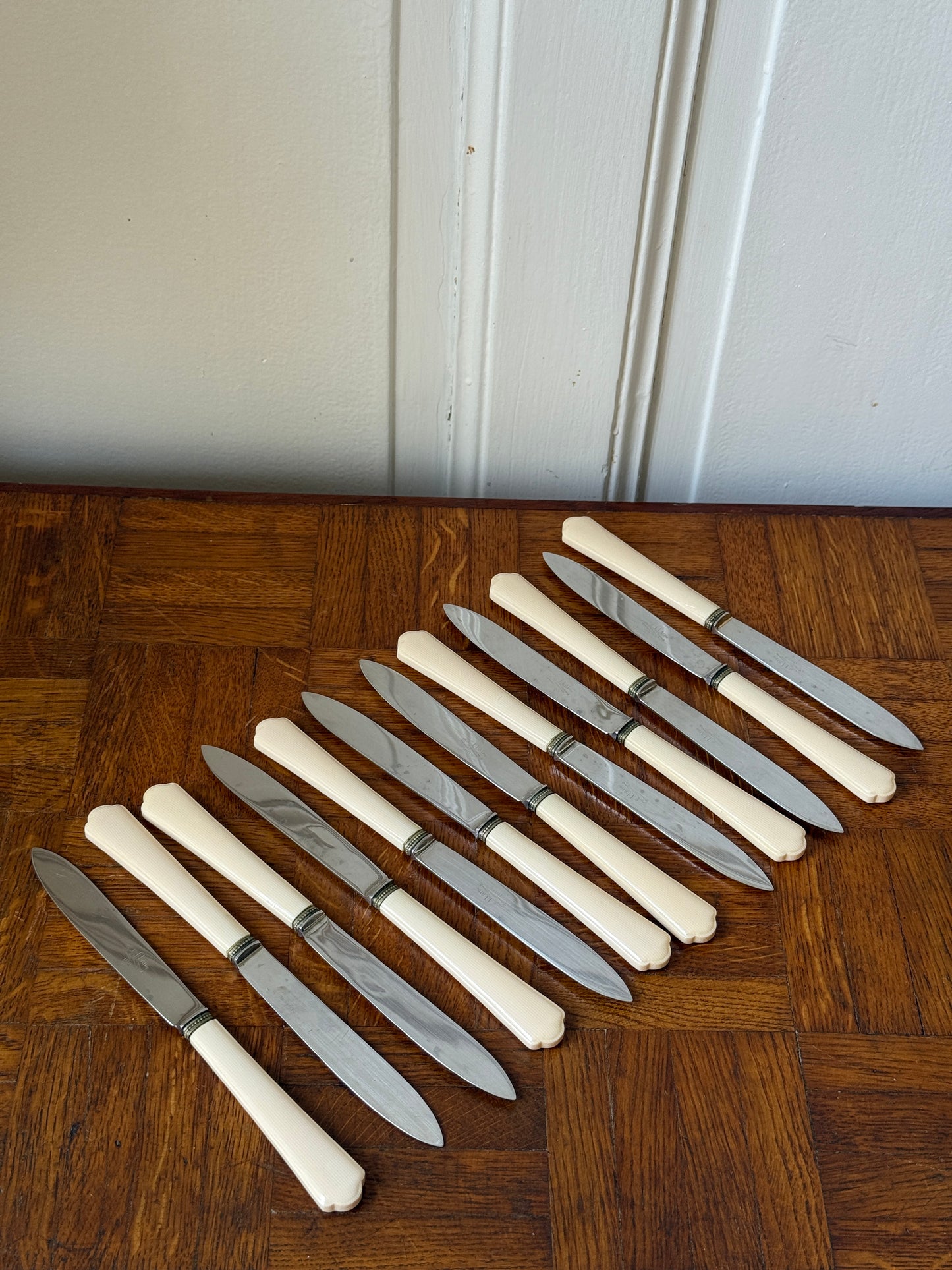 Coffret de 24 couteaux Art Déco Razzia, maison P. Prély, avec manches en bois et lames en acier inoxydable, présenté dans un coffret élégant.