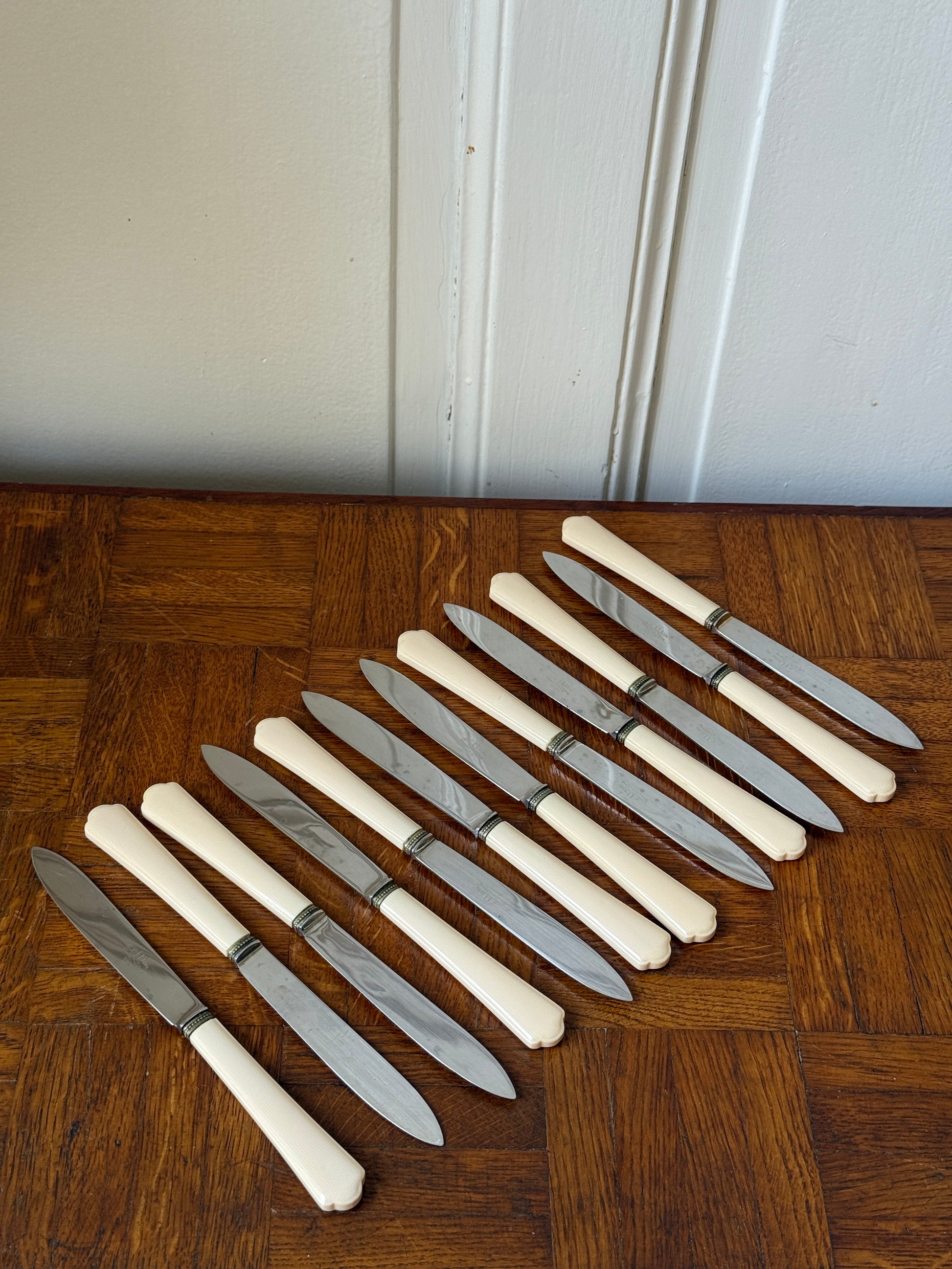 Coffret de 24 couteaux Art Déco Razzia, maison P. Prély, avec manches en bois et lames en acier inoxydable, présenté dans un coffret élégant.