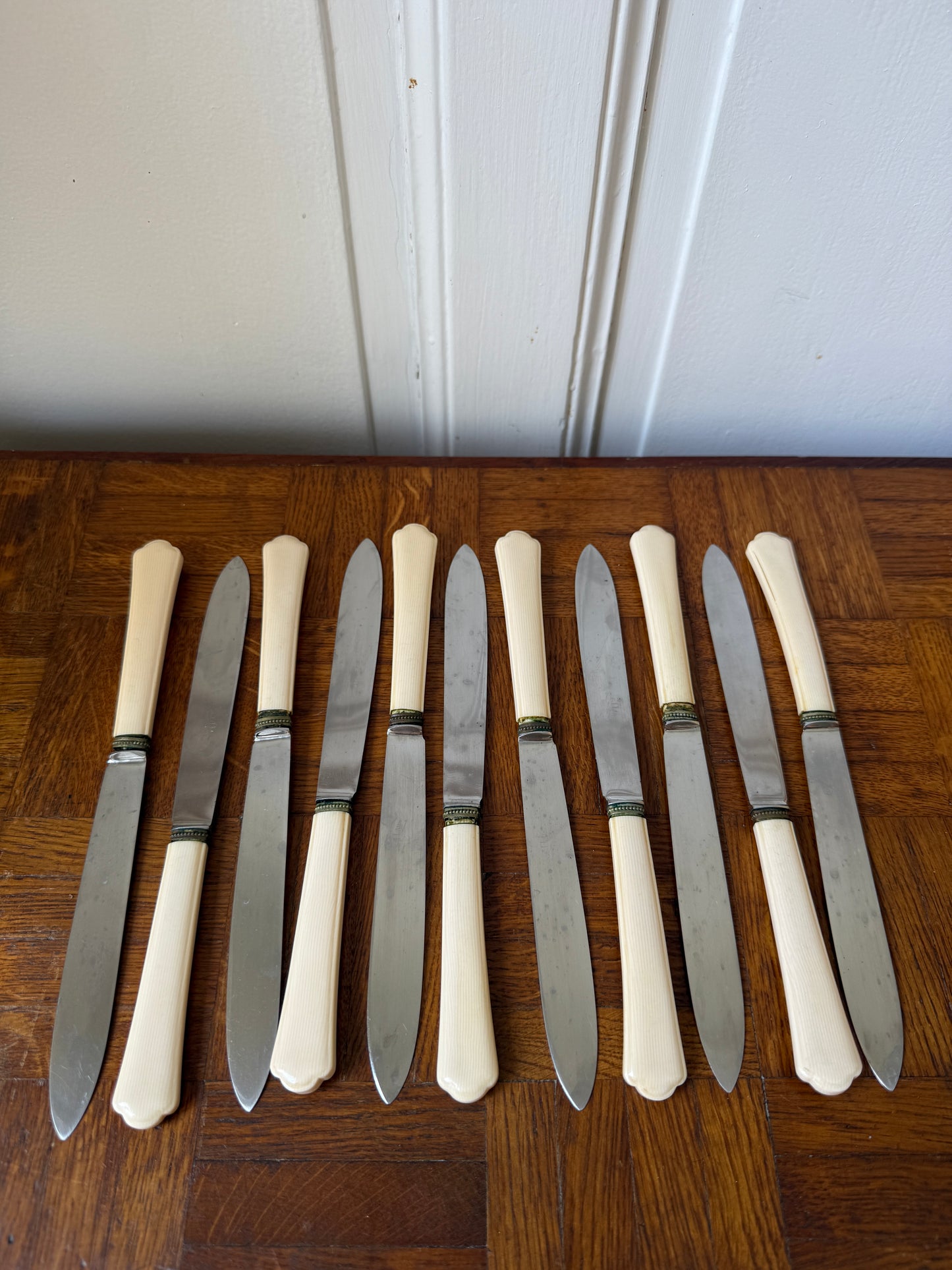 Coffret de 24 couteaux Art Déco Razzia, maison P. Prély, avec manches en bois et lames en acier inoxydable, présenté sur une table.