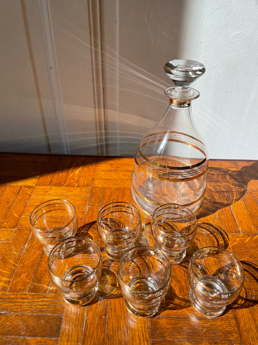 Vintage Razzia Days carafe and liqueur glasses set, clear glass with elegant design, on a wooden surface.