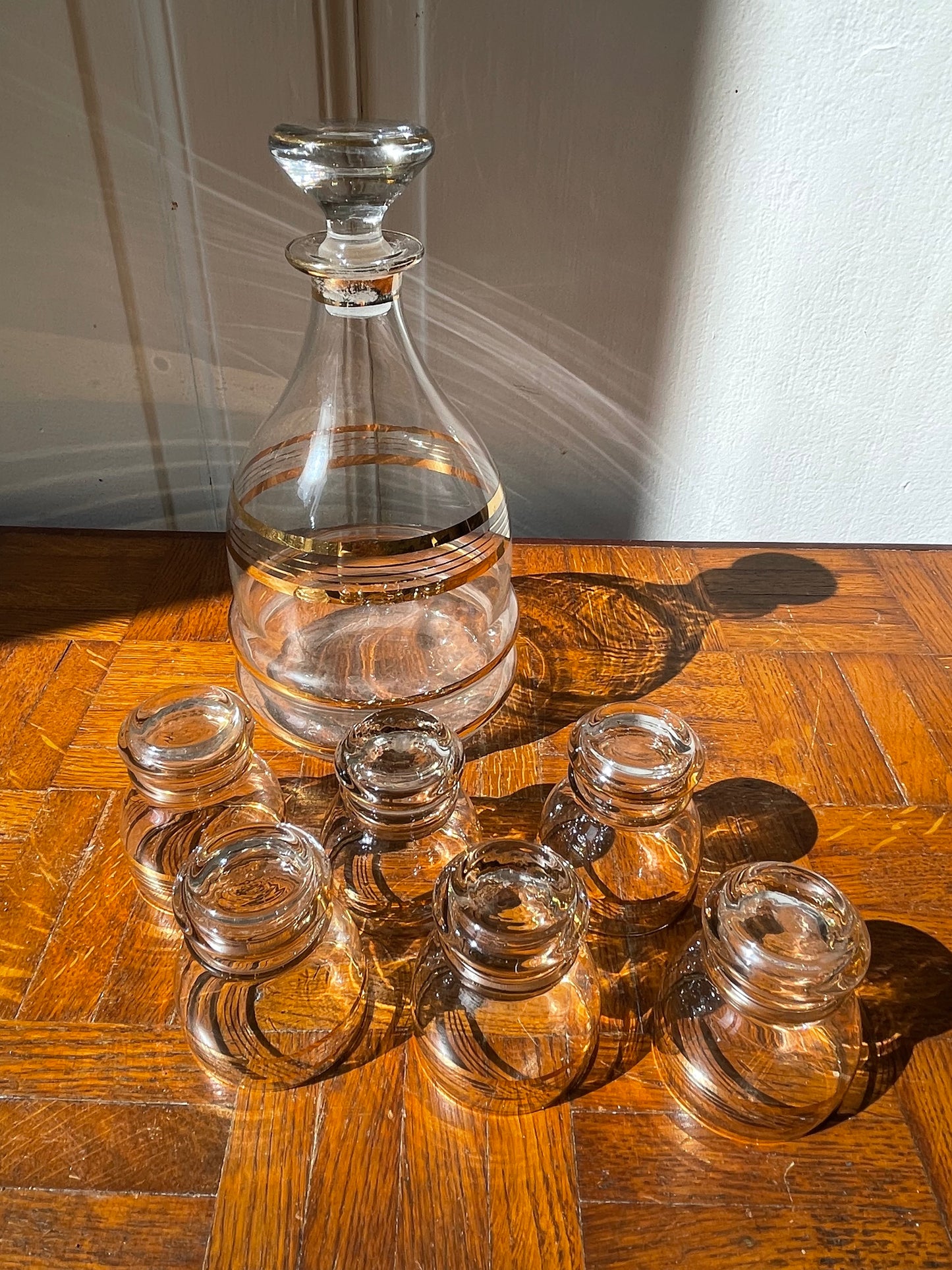 Vintage Razzia Days carafe and liqueur glasses set with clear glass and elegant design, displayed on a wooden surface.